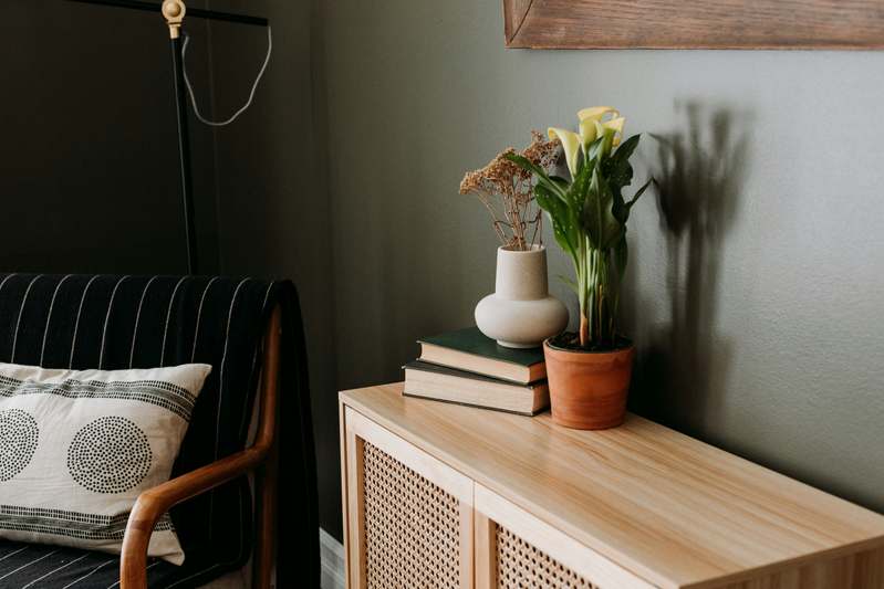 Woman styling a boho-inspired bedroom with plants and macramé
